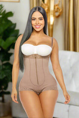 Woman wearing a beige shapewear bodysuit with a white bra on a white background
